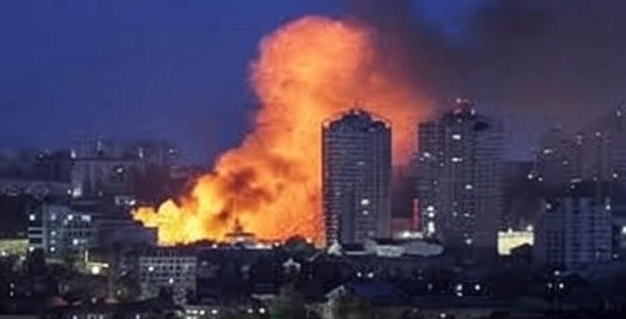 Massive fire and smoke engulf a Ukrainian city at night, with buildings silhouetted, reflecting a Russian assault on June 28-29, 2025.