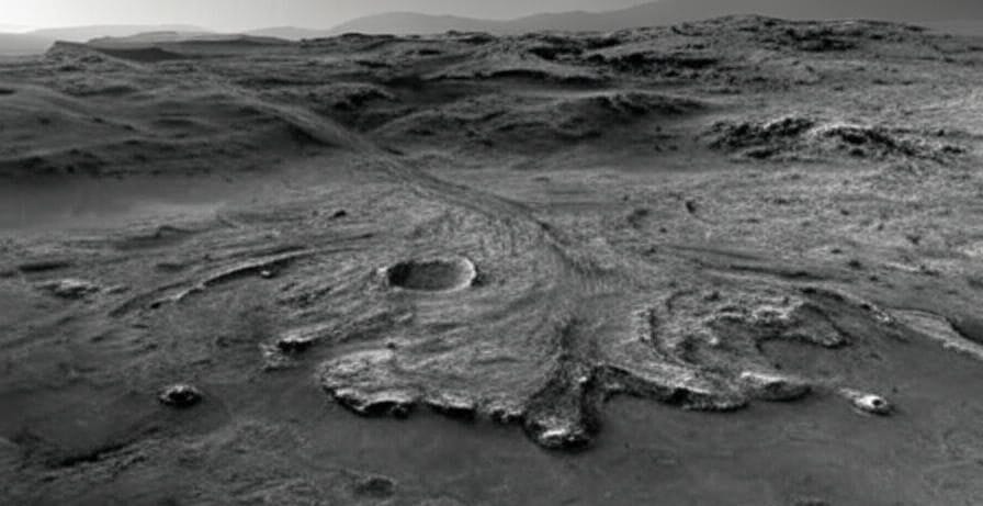 Image of a Martian landscape featuring a large crater with radiating patterns, captured in a reddish terrain, indicative of geological features explored by NASA's Perseverance rover.
