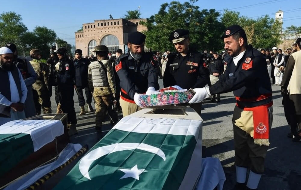 Pakistani police officers in ceremonial uniforms solemnly place a floral wreath on a coffin draped in the national flag during a funeral procession for security personnel killed in cross-border clashes with Afghan Taliban forces along the Durand Line, amid escalating tensions and Defence Minister Khawaja Asif's ultimatum on October 29, 2025.